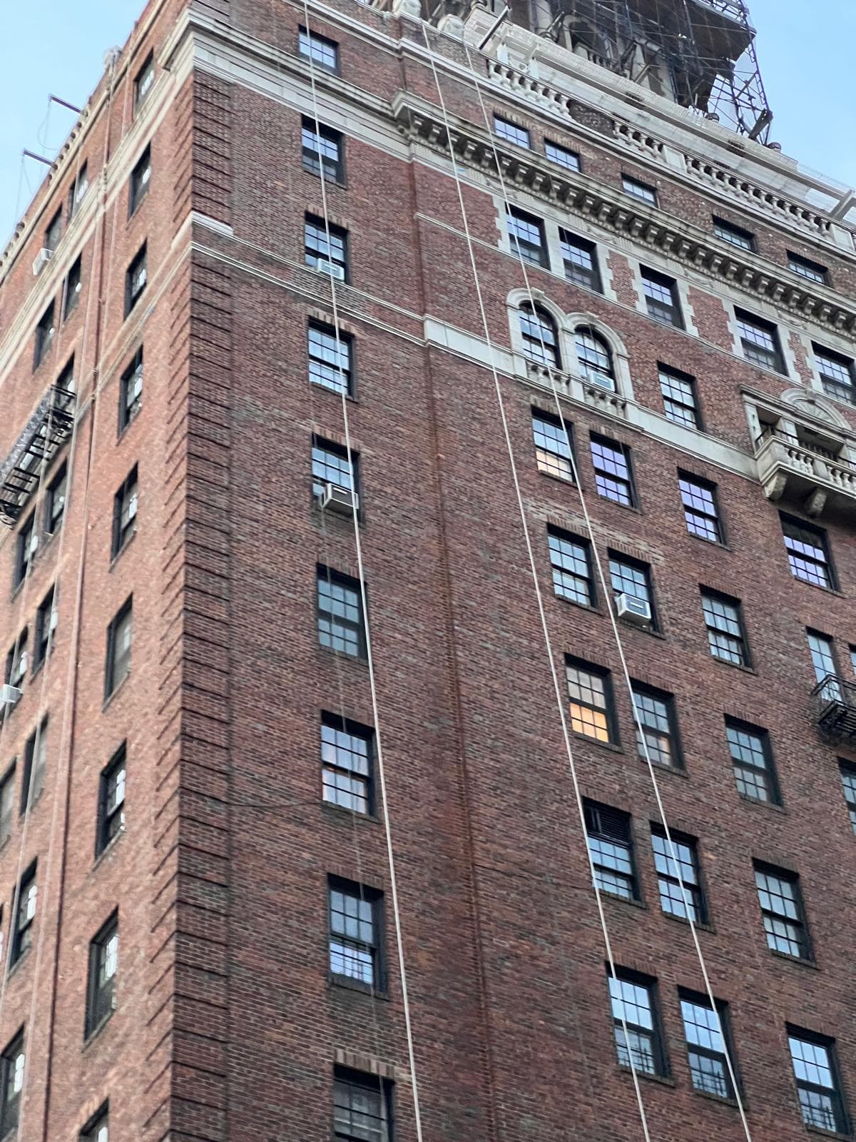 Brick high-rise under facade inspection with restoration cables running down the elevation